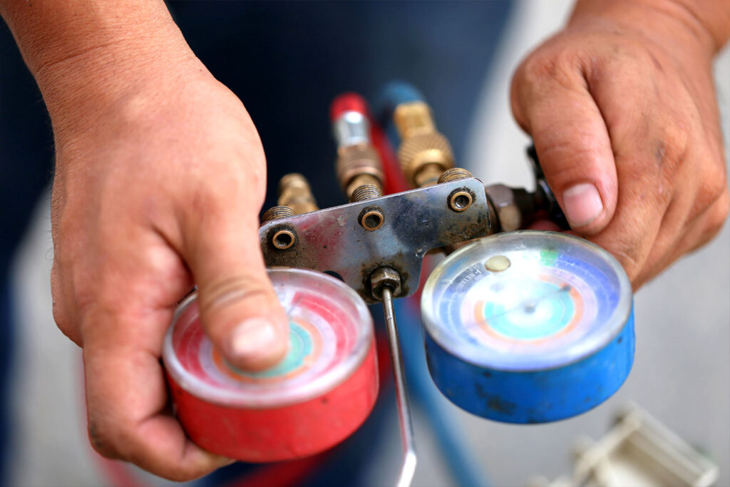 Hands operating a refrigerant manifold gauge on BMW and Audi AC repair services hvac system.