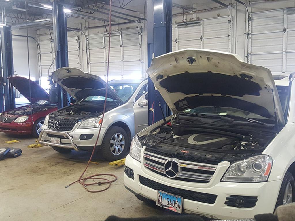 Vehicles undergoing maintenance in an auto repair shop with open hoods.